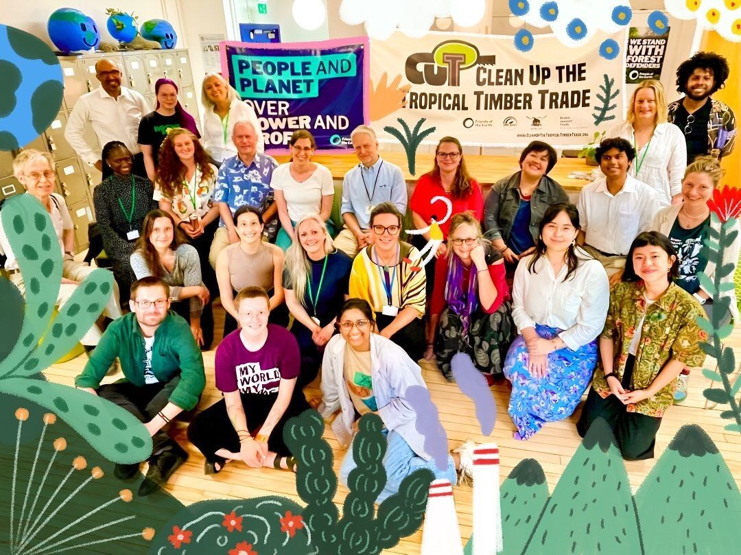 A diverse group of people gathered and smiling in front of a colorful sign.