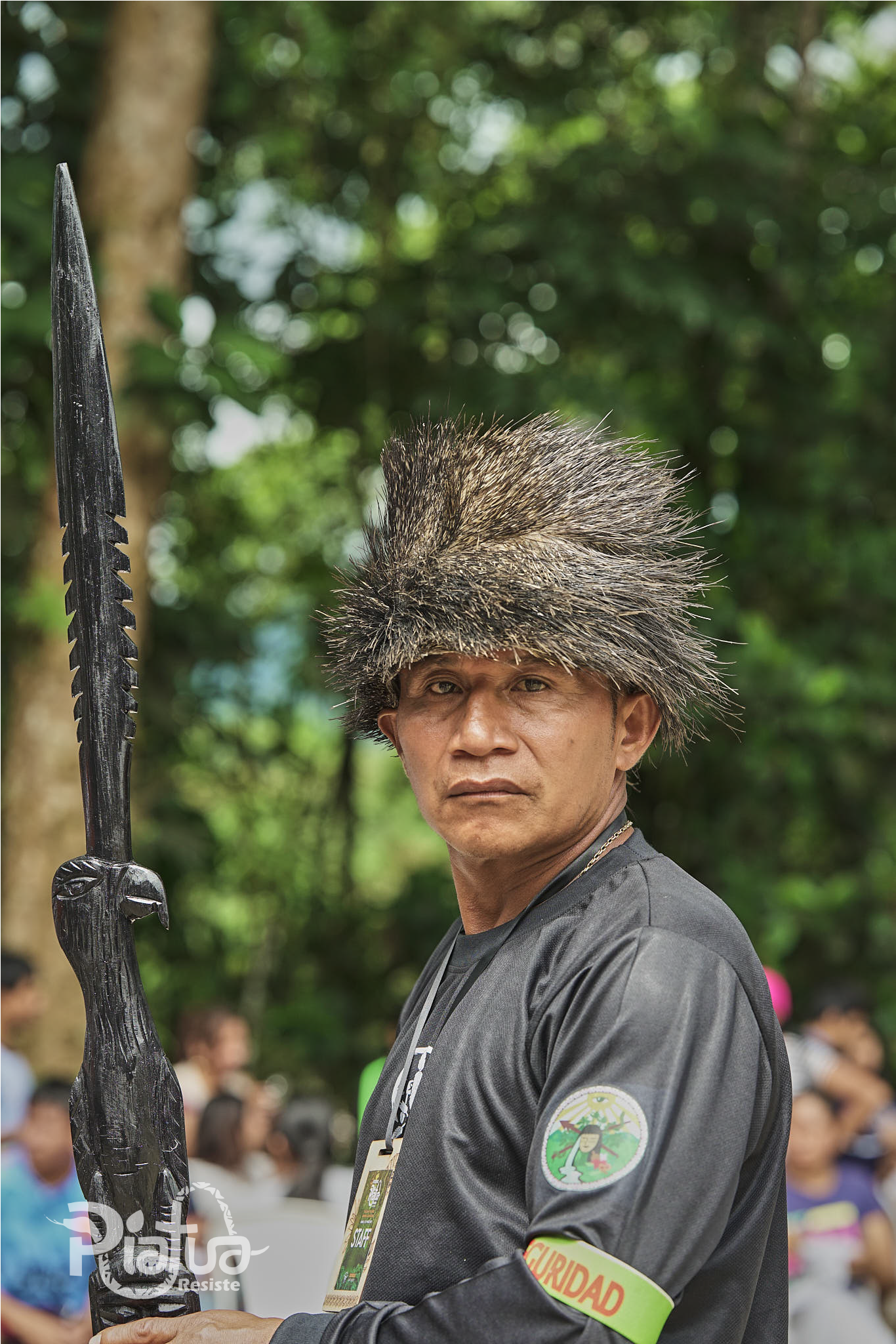 Indigenous guard in the Ecuadorian Amazon, wearing a crown made of porcupine quills and holding a carved staff, during a demonstration in defense of the Piatua River.